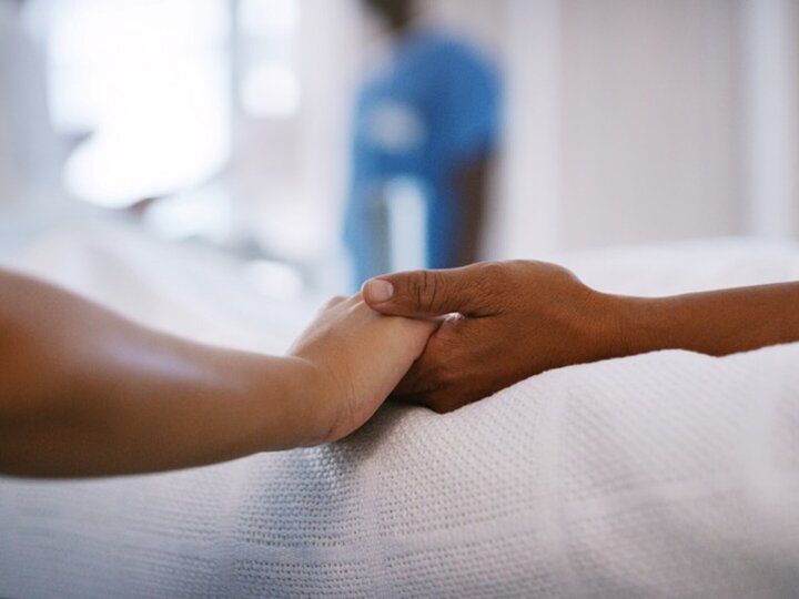 two people holding hands in hospital bed
