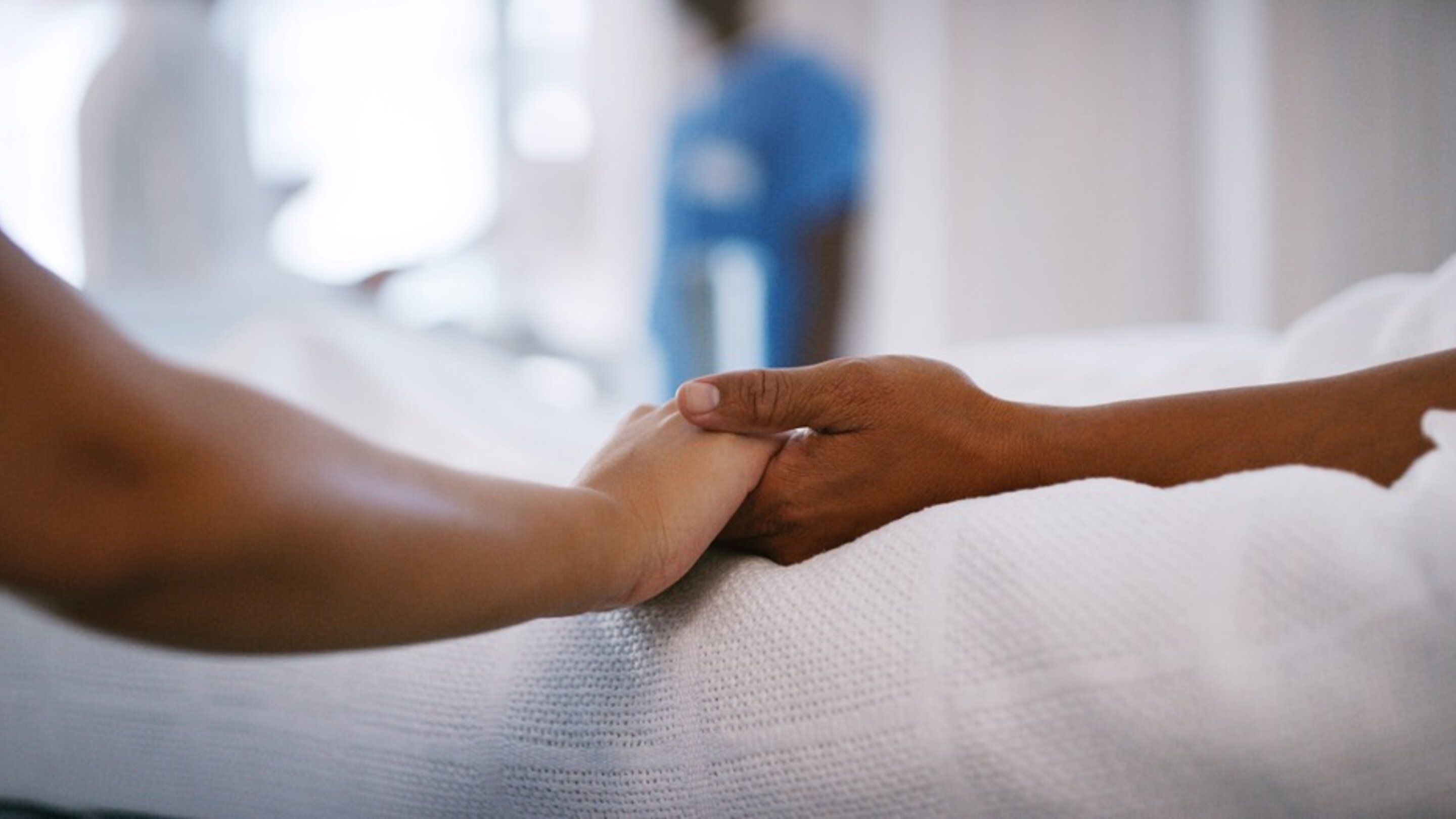 two people holding hands in hospital bed