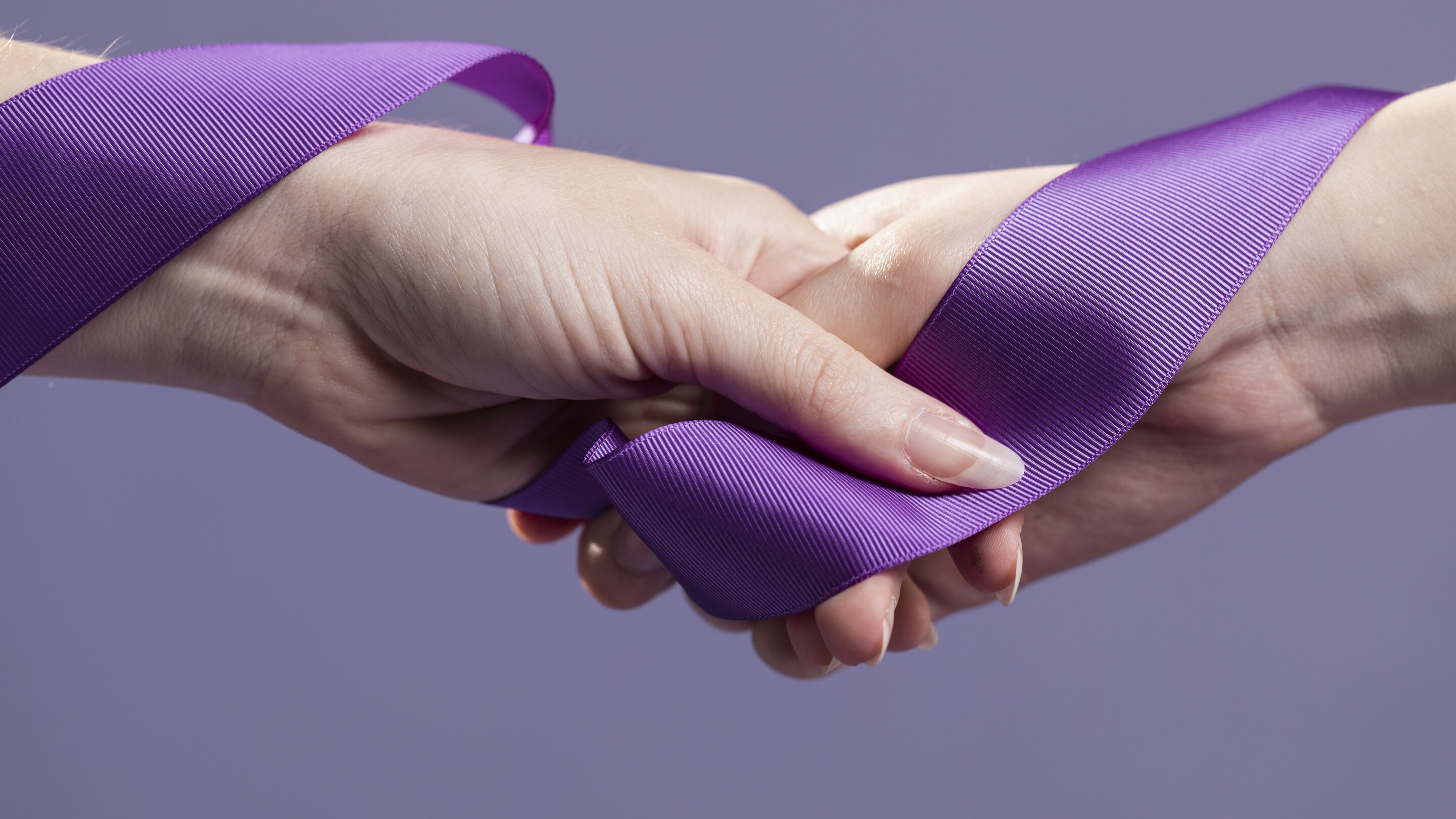 women hands holding purple ribbon