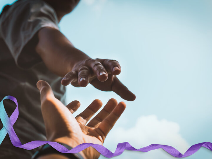 person reaching out to another hand with ribbon