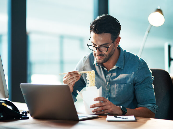 man eating lunch at computer